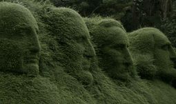 heads carved into a hedge 