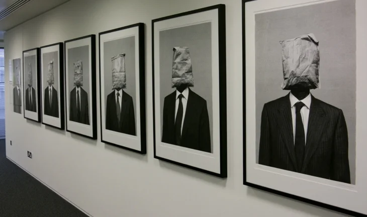 photographs on the wall of an office. The people have teabags for heads